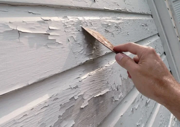 Deteriorated exterior paint being scraped away before repainting