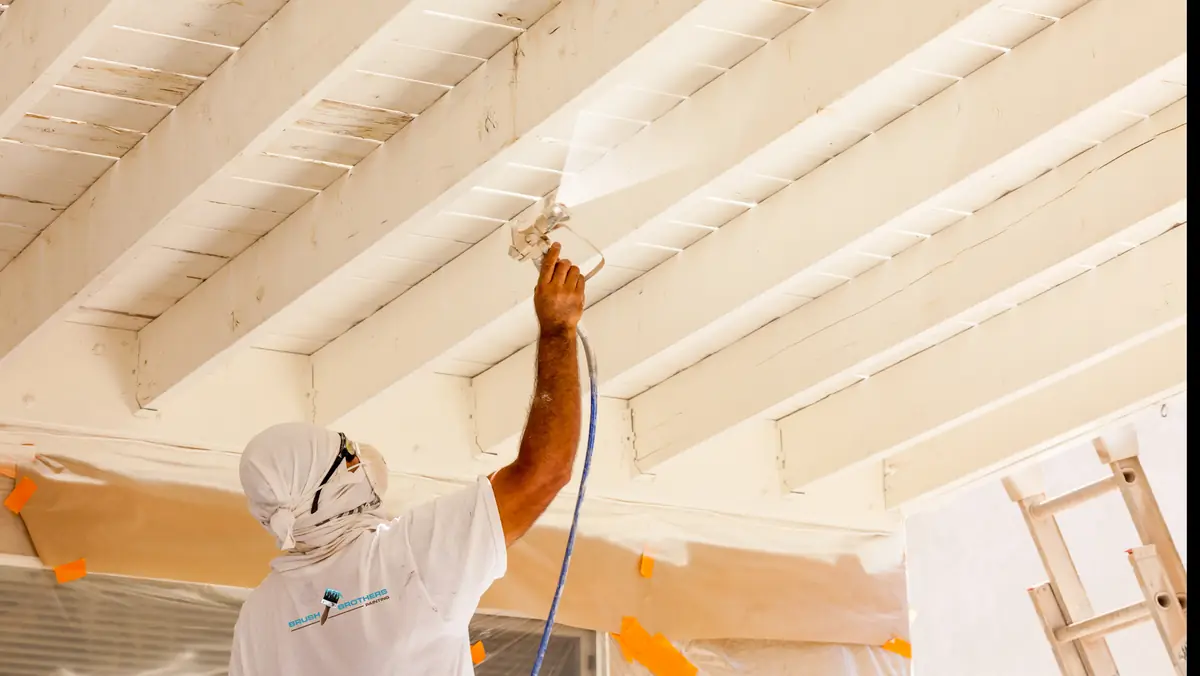 Brush Brothers painter spraying a ceiling with surrounding surfaces carefully protected